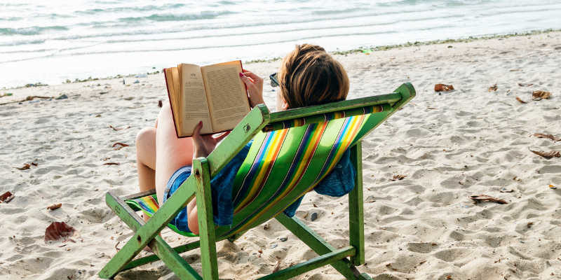 woman reading book on beach
