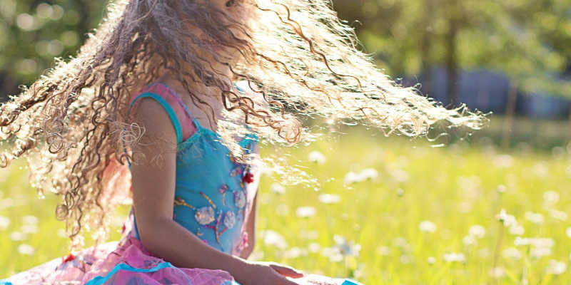 girl twirling in field of summer daisies